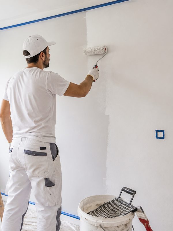 Peintre en bâtiment appliquant la peinture au rouleau, assuré en décennale avec AAMI Assurances
